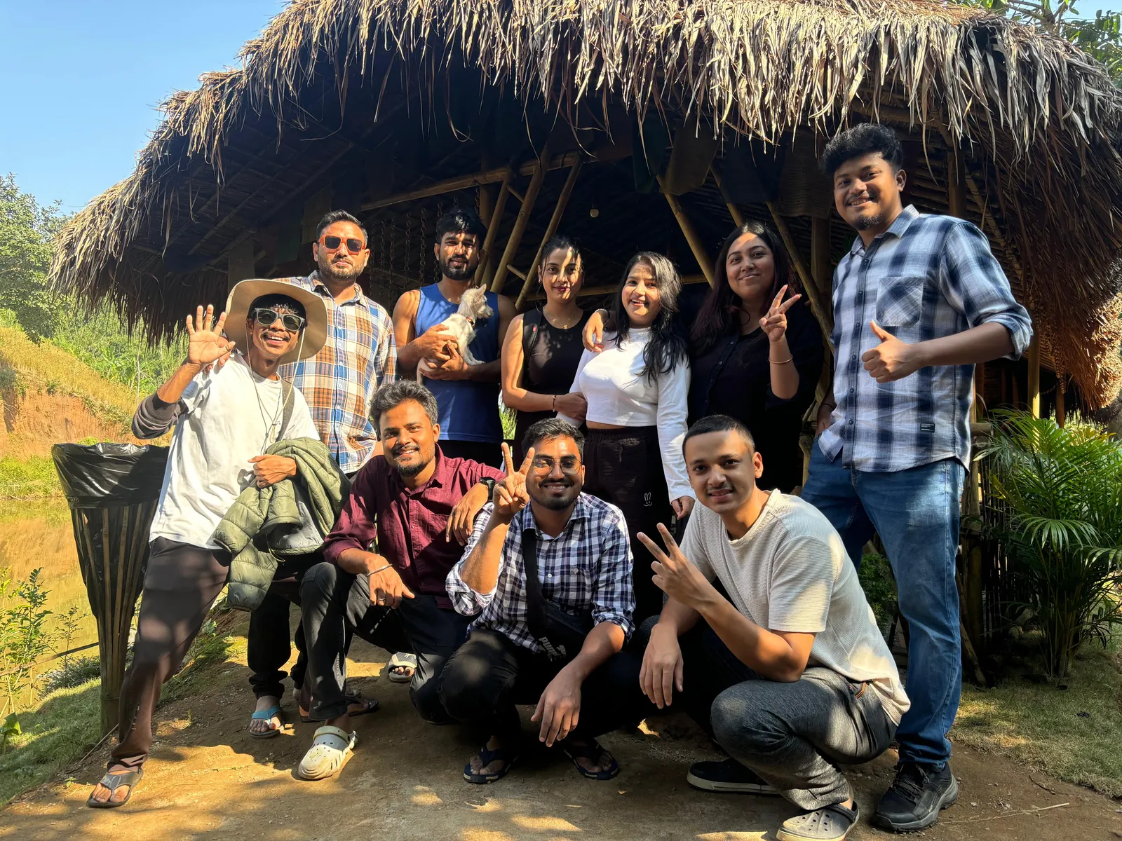 A group of guests together outside a thatched bamboo shelter at Mridu